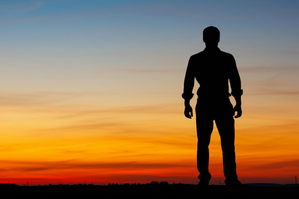 A silhouette of a confident man standing tall against a sunset backdrop