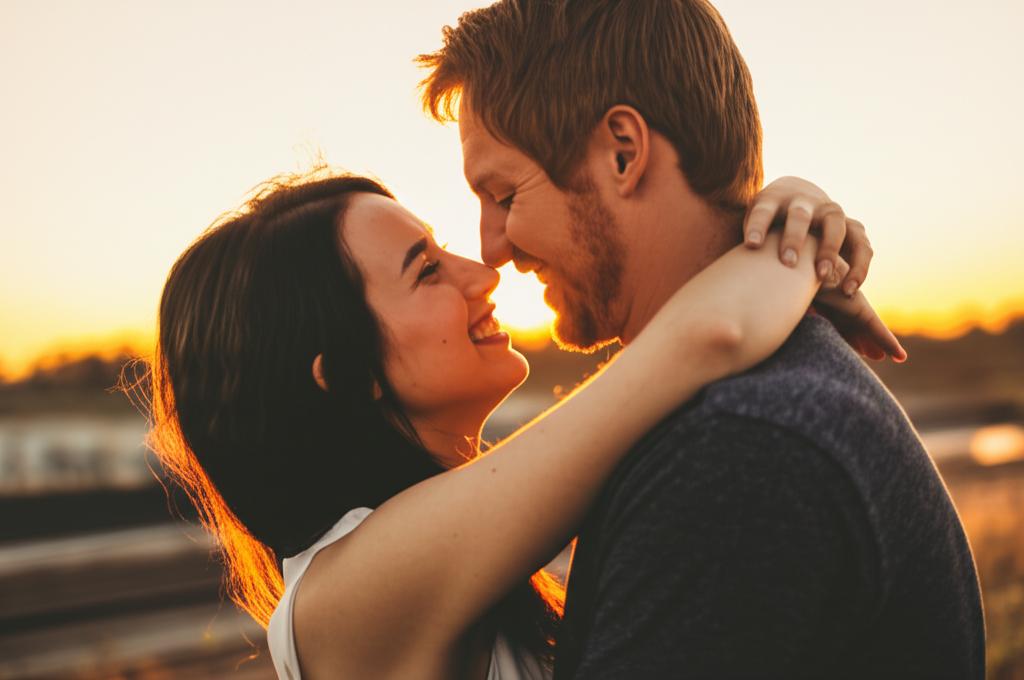 A couple hugging and smiling at each other at sunset.