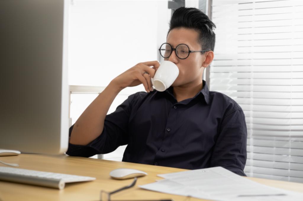 ai_prompt_tired_man_drinking_coffee_at_desk_singapore_office